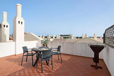 a patio with a table and chairs on a roof at Apartamento Old Village T2 Duplex in Quarteira