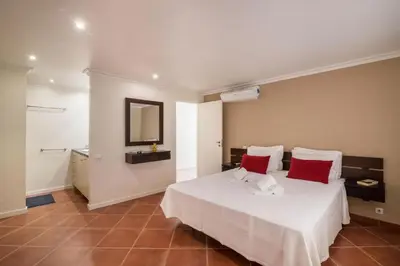 a bedroom with a white bed with red pillows and a mirror at Apartamento Malick by Sunnyway in Branqueira