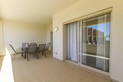 a dining room with a table and chairs and a balcony at Millennium Plaza in Vilamoura