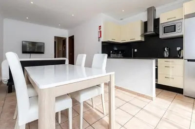 a kitchen and dining room with a white table and chairs at Akisol Albufeira Water in Albufeira