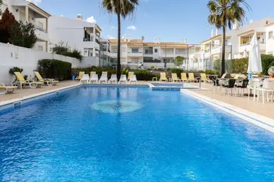 a swimming pool in a hotel with chairs and tables at Akisol Albufeira Water in Albufeira