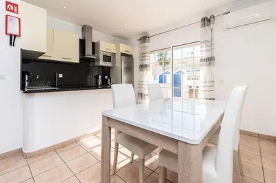 a kitchen and dining room with a white table and white chairs at Akisol Albufeira Water in Albufeira