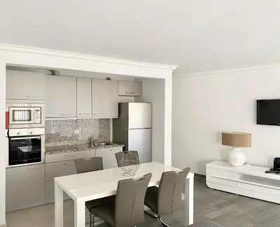 a white kitchen with a white table and chairs at Ténis Studio Apartment - Vilamoura in Vilamoura