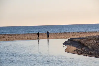 two people standing on the beach looking at the water at Apartment Salgados Lounge - By Dalma Portuguesa in Albufeira