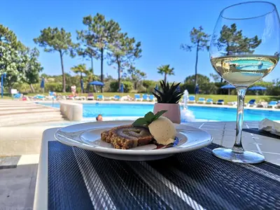 a plate of food and a glass of wine on a table at Victory Village 20B in Quinta do Lago