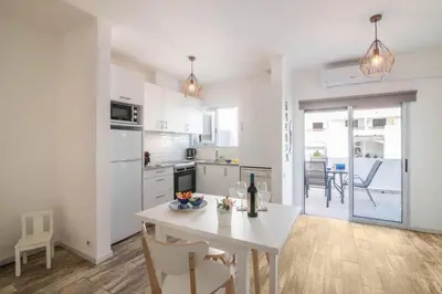 a white kitchen with a white table and chairs at Apartamento Patrick by Sunnyway in Albufeira