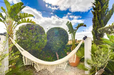 a hammock in front of a garden with trees at Vila Rafa in Albufeira