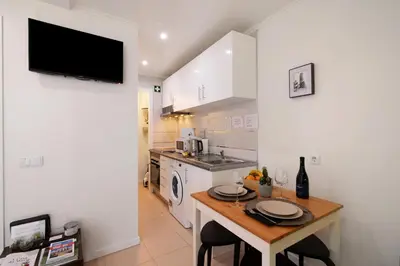 a kitchen with a table with chairs and a tv on the wall at Casa Maria in Faro