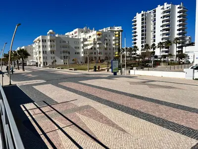 an empty street with tall buildings in the background at Terraços Quarteira 2D3 in Quarteira
