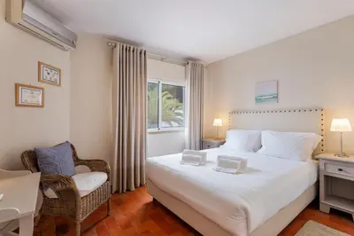 a bedroom with a large white bed and a chair at Townhouse Seraphina in Vale do Lobo