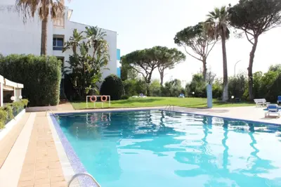 a swimming pool in a resort with palm trees at Lago Azul Apartment II in Quarteira