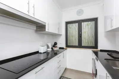 a kitchen with white cabinets and a black counter top at Miral 3 - Sea front by HD PROPERTIES in Quarteira