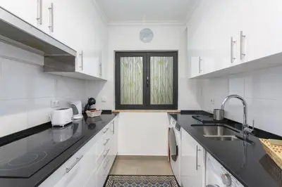 a kitchen with white cabinets and black counter tops at Miral 3 - Sea front by HD PROPERTIES in Quarteira