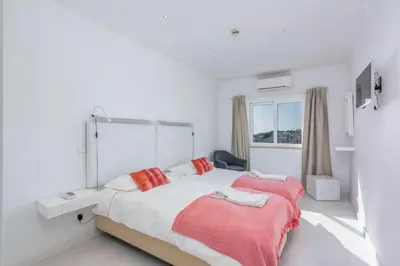 a white bedroom with a large bed and a window at Old Town Beach Apartments in Albufeira