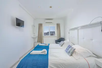 a bedroom with a large white bed with a blue blanket at Old Town Beach Apartments in Albufeira