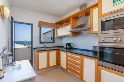 a kitchen with wooden cabinets and a view of the ocean at Old Town Beach Apartments in Albufeira