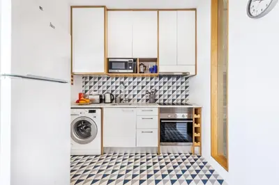 a kitchen with white cabinets and a washer and dryer at RG Sunny Ap in Faro
