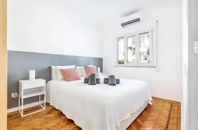 a white bedroom with a large white bed with red pillows at RG Sunny Ap in Faro