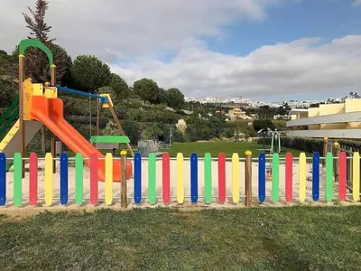 a colorful wooden fence in front of a playground at MARINA BLEU Magnifique Appartement Standing vue Piscine in Albufeira