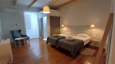 a bedroom with a large bed and a chair at A Casa do Tenente in Faro