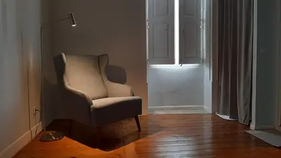 a living room with a chair and a lamp at A Casa do Tenente in Faro