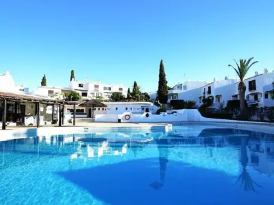 a large blue swimming pool with white buildings in the background at Vue mer et piscine à 5 min à pied de Praia Sao Rafael Albufeira in Albufeira