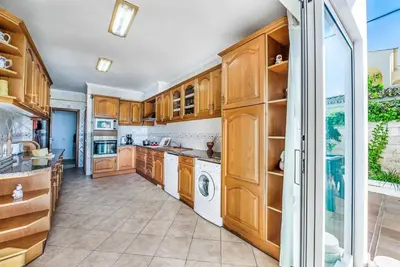 a kitchen with wooden cabinets and a washer and dryer at Villa Oceano in Patroves