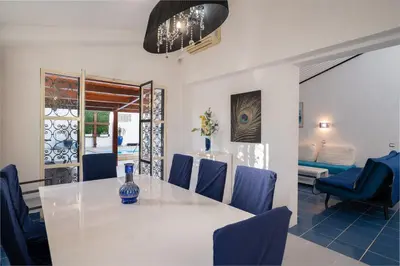 a dining room with a white table and blue chairs at Villa Vitry by Intiholidays in Albufeira