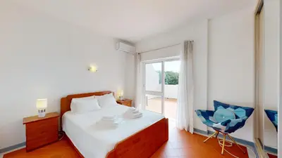 a bedroom with a bed and a chair and a window at Apartamento Tranquilo T1 Albufeira 002 in Albufeira