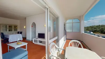 a room with a balcony with a table and a television at Apartamento Tranquilo T1 Albufeira 002 in Albufeira