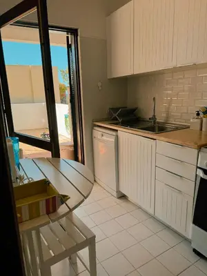 a kitchen with white cabinets and a sink and a table at T2 sobre a praia - Albufeira/Olhos de Água in Albufeira