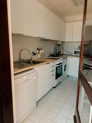 a kitchen with white cabinets and a sink and a dishwasher at T2 sobre a praia - Albufeira/Olhos de Água in Albufeira
