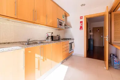 a kitchen with wooden cabinets and a sink at Corcovada Albufeira 1 Quarto by Glenge Holiday in Albufeira