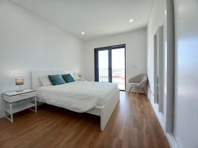 a white bedroom with a bed and a window at T3 Alto Forte -Vista Mar,Ar Condicionado,Garagem in Quarteira