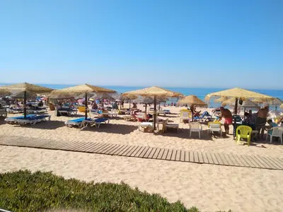 a beach with umbrellas and people sitting on the sand at T1 BOAVISTA 6 VISTA MAR Wi-Fi Ar Cond in Quarteira