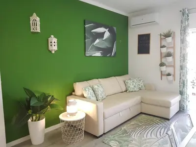 a living room with a couch and a green wall at T1 BOAVISTA 6 VISTA MAR Wi-Fi Ar Cond in Quarteira