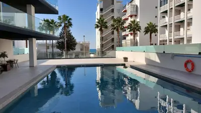 a swimming pool in a building with palm trees at Apartamento Meerblick in Quarteira