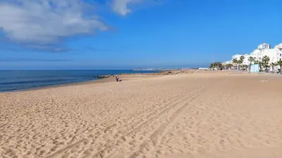 a beach with footprints in the sand and the ocean at Apartamento Meerblick in Quarteira