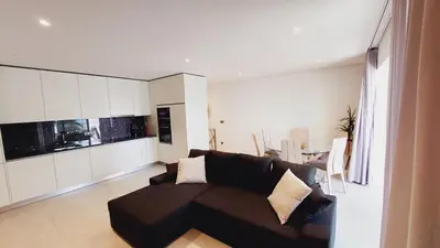 a living room with a brown couch and a kitchen at Apartamento Meerblick in Quarteira