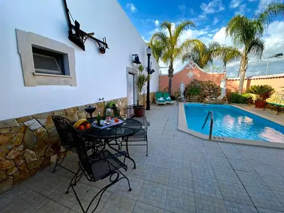 a patio with a table and chairs next to a swimming pool at Palma's Place Casanova Villa #WIFI#HEATEDPOOL#RELAX in Faro
