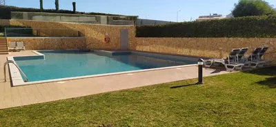 a swimming pool with two chairs and a wall at Appartement Standing au coeur d'Albufeira in Albufeira