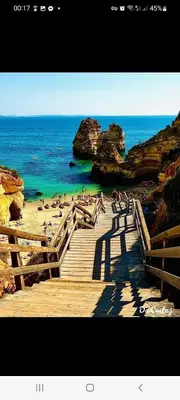 a wooden staircase leading to a beach with people on it at Appartement Standing au coeur d'Albufeira in Albufeira