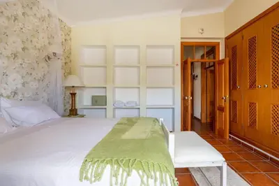 a bedroom with a white bed with a green blanket on it at Monte Velho in Loulé