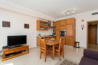 a kitchen and dining room with a table and a television at São João das Areias By Albufeira Rental in Albufeira