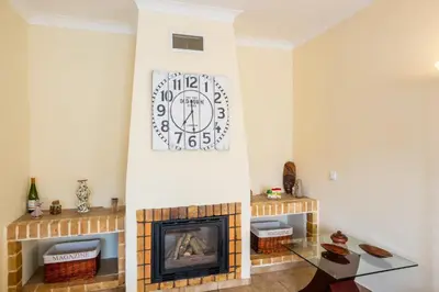 a living room with a fireplace and a clock on the wall at Villa Sequeira - Private Pool - Free WIFI - BY BEDZY in Albufeira