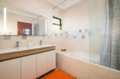 a white bathroom with a tub and a sink and a bath tubermott at Villa Sequeira - Private Pool - Free WIFI - BY BEDZY in Albufeira