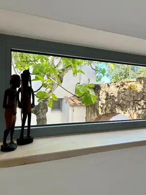 two dolls standing on a window sill looking at a tree at Stilvolles Architekten-Cottage mit Pool in Boliqueime