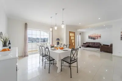 a dining room and living room with a table and chairs at Villa Lemos by HelloVacations in Albufeira