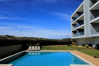a swimming pool with two chairs and a building at Albufeira Prestige With Pool by Homing in Albufeira