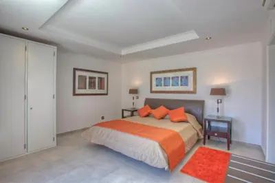 a bedroom with a bed with orange pillows and a red rug at Casa da Horta in Almancil